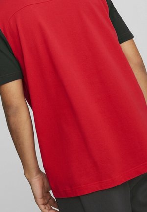 Czerwona i czarna koszulka z krótkim rękawem o luźnym kroju; charakteryzuje się gładką bawełnianą fakturą z kontrastującymi rękawami i czystym wykończeniem dolnej krawędzi.