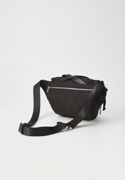 Black quilted fabric bag with a zippered front pocket and adjustable strap. Features a rounded shape and smooth texture.