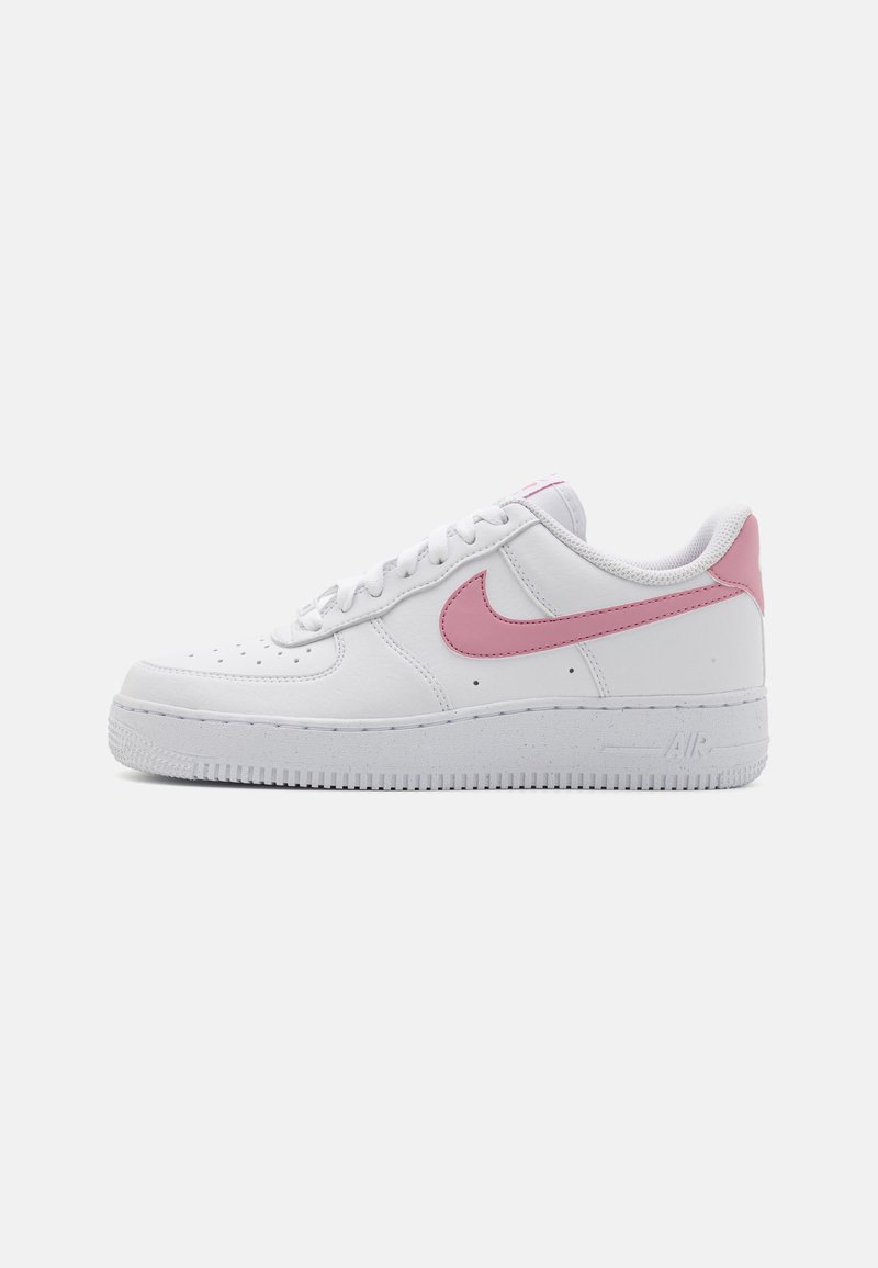 Biele tenisky Nike Air Force 1 s ružovými akcentmi, hladký kožený zvršok, perforovaný dizajn špičky, ploché šnúrky a gumová podrážka.