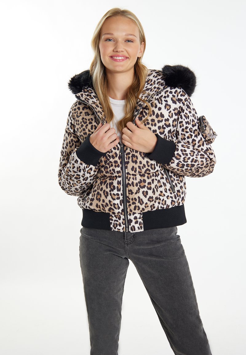 Giacca bomber con stampa leopardata e cappuccio in finta pelliccia nera, chiusura con zip, tasche laterali e polsini a costine. Abbinata a pantaloni grigi scuri.