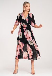 Czarna sukienka w kwiaty z różowymi i niebieskimi motywami, plisowany krój, styl kopertowy, krótkie rękawy oraz wcięta talia z srebrnym paskiem.