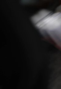 Zamagljena slika s tamnom pozadinom; vidljive svjetlosne refleksije na glatkim površinama, koje sugeriraju metalne ili plastične materijale; nejasni detalji.