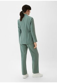 Groene blazer met een elastische taille en bijpassende broek. Gemaakt van gladde stof, met lange mouwen en een getailleerde silhoutte.