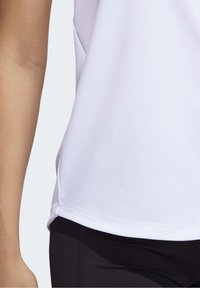 Hvid atletisk skjorte med blød tekstur, korte ærmer og afrundet kant, kombineret med sorte leggings. Enkel design uden synlige mønstre.