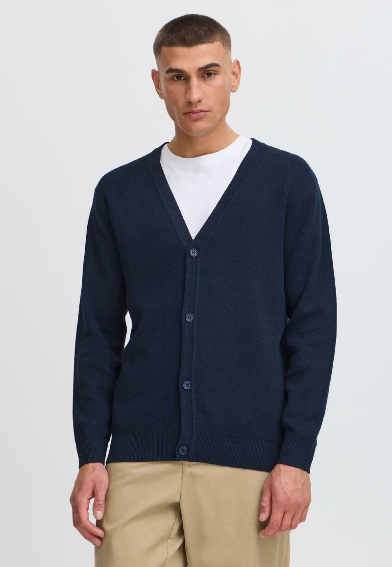Mörkblå cardigan med V-ringning, långa ärmar och knappar framtill. Tillverkad av ett mjukt material, designad för en figursydd look.