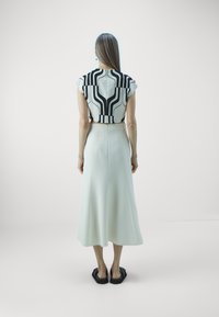 White midi skirt paired with a cropped top featuring a black and white geometric pattern. Smooth fabric, loose fit, and relaxed silhouette.