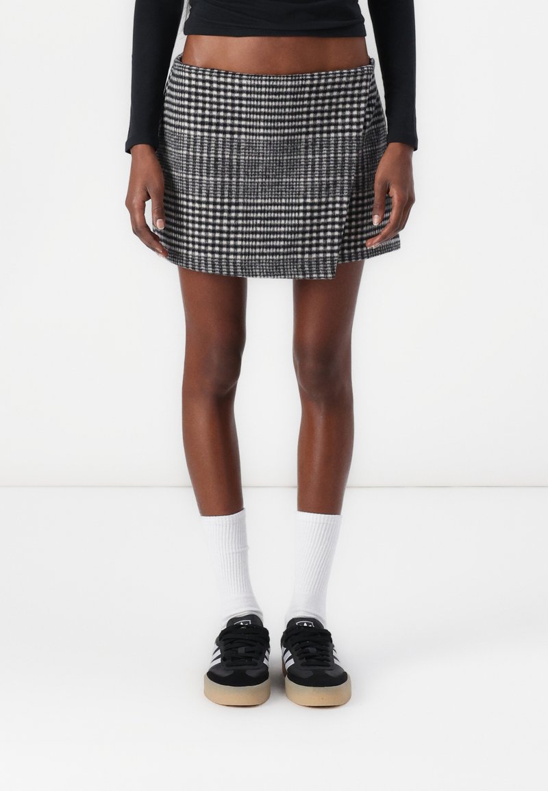 Zwart-wit geruit minirok met rechte snit, textuurstof en een zijsplits. Gecombineerd met zwarte sneakers en witte sokken tot de crew.