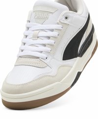 Hvide og grå sneakers lavet af læder og ruskind, med sorte accenter, en struktureret tå og en gummisål med et særpræget mønster.