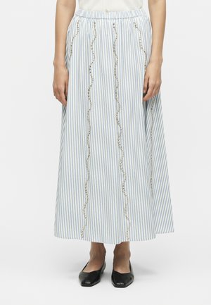 Sinine ja valge vertikaalsete triipudega midi seelik lainekujuliselt hõbedaste helmestega kaunistustega, kantud mustade lamedate kingade ja valge topiga.