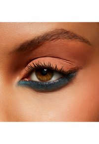 Close-up van een oog met bronzen oogschaduw en blauwe eyeliner. Het heeft lange wimpers, een warme bruine iris en een gladde huidtextuur.