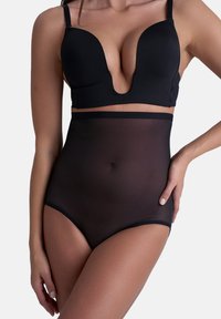 Reggiseno nero con scollo profondo, coppe lisce e sagomate, e spalline regolabili abbinato a shapewear nero trasparente a vita alta. Vita regolabile.