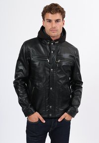 Černá kožená bunda s zipovými hrudními kapsami, patentními knoflíky a skládacím límcem, s hladkou texturou a přiléhavým střihem.