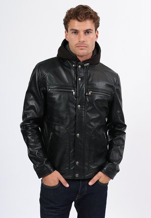 Chaqueta de cuero negro con bolsillos en el pecho con cremallera, cierres a presión y un cuello doblado, con una textura suave y un diseño ajustado.