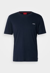 T-shirt à manches courtes bleu marine avec col rond, petit logo blanc "HUGO" sur la poitrine gauche et étiquette rouge à l'intérieur du col.