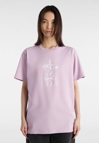 Camiseta de algodón de color púrpura claro con mangas cortas y escote redondo, que presenta un gráfico blanco de un conejo de dibujos animados y el logotipo de "Vans".