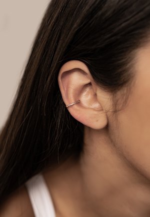 Silver hoop earring with a minimalist design, featuring a smooth surface and a subtle sparkle effect from embedded small stones.