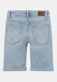 Pantalones cortos de mezclilla azul claro con dobladillos enrollados, diseño de cinco bolsillos y una etiqueta de cuero marrón en la parte trasera de la cintura.