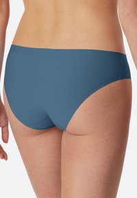 Modré hipsterské slipy z hladké tkaniny mají nízký pas a bezešvé okraje pro elegantní a pohodlné nošení.