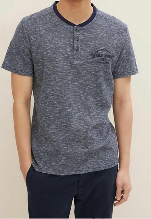 Marineblauwe t-shirt met korte mouwen, een subtiele gestreepte patroon, ronde halslijn, twee knopen en een bedrukte tekst op de borst.