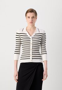 Cardigan à rayures blanches et noires avec une texture côtelée, fermeture à boutons, col en V et manches trois-quarts. Accent doré au niveau du bas des manches.