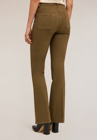 Pantalones marrones acampanados con una textura suave, que cuentan con dos bolsillos traseros y una cinturilla. Combinados con zapatos de tacón negros.