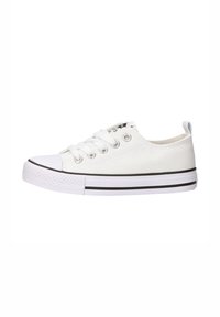 Zapatilla de lona blanca con puntera de goma, raya negra en la suela y seis ojetes para los cordones. Presenta una pestaña en la parte trasera para ponérsela fácilmente.