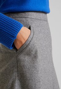Grijs wollen blend rok met zijzak en schone naden, gecombineerd met een blauwe gebreide trui met geribbelde manchetten.