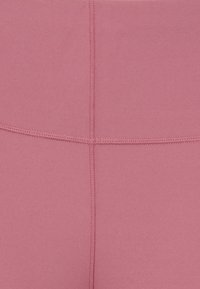 Leggings rosa com um tecido suave e elástico. Apresenta costuras planas e um notável design de costura cruzada na parte de trás.