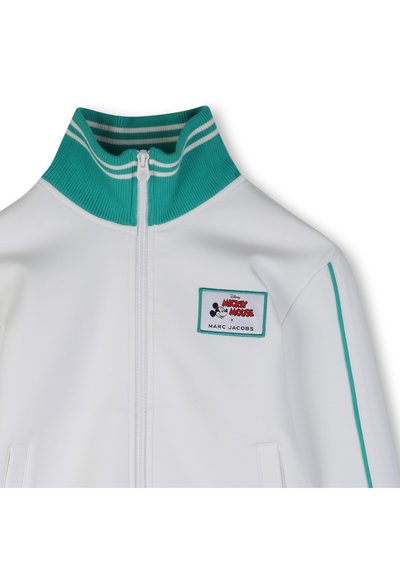 Λευκό μπουφάν με φερμουάρ, διαθέτει τυρκουάζ ριμπ περιλαίμιο με λευκές ρίγες, πλαϊνές τσέπες και ένα μοτίβο με τα λ όγια "Mickey Mouse x Marc Jacobs".
