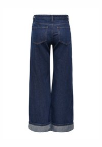 Jean bleu foncé à jambes larges avec ourlets roulés et poches arrière, vu de dos sur fond blanc.