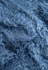 Niebieska koronka z wzorem kwiatowym z fakturą, zawierająca szczegółowe detale i teksturowane wykończenie, tworząca warstwowy, trójwymiarowy efekt.
