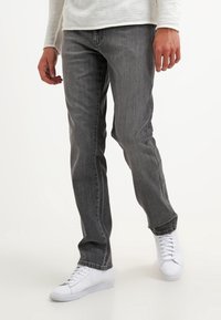 Grå denimjeans med rak passform, med en klassisk femficksdesign och subtila slitningar, i kombination med vita sneakers.