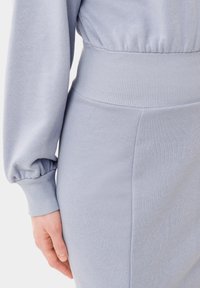 Felpa azzurra chiara a coste con una vita ampia e maniche a sbuffo. Il tessuto ha una texture liscia, che valorizza un design aderente.