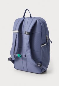 Backpack in dark blue fabric, featuring padded straps, a top handle, mesh side pocket, reflective accents, and a plastic fastener.