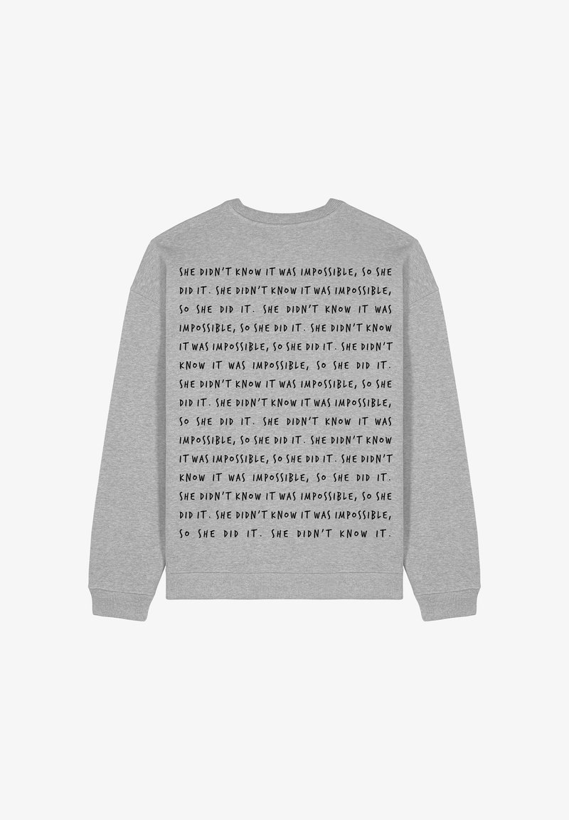 Grå sweatshirt med upprepat textmönster i svart. Rundad hals, långa ärmar, ribbade muddar och nederkant. Texten lyder: "hon visste inte att det var omöjligt, så hon gjorde det."