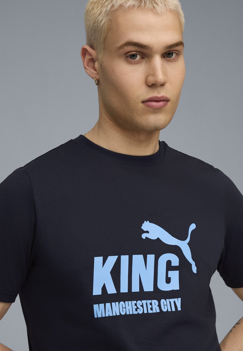Marin bombažna majica z dolgimi rokavi z napisom "KING" in "MANCHESTER CITY" v svetlo modri barvi, z svetlo modrim logotipom Puma nad besedilom.