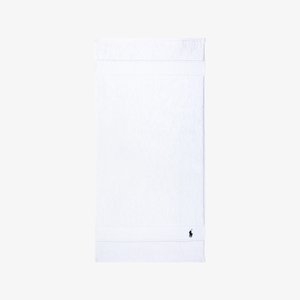 Asciugamano da bagno in cotone bianco, superficie strutturata, bordi orlati, con un logo blu navy nell'angolo inferiore. Forma rettangolare semplice.