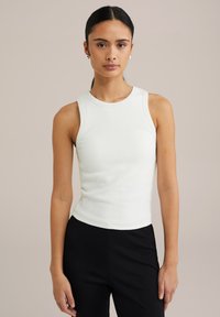 Hvid ribbet tanktop med rund halsudskæring og ærmeløst design, tætsiddende form, parret med sorte bukser for kontrast.