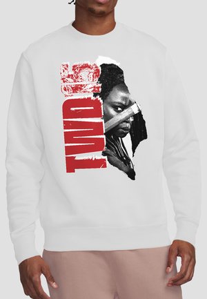 Person wearing a white sweatshirt with a graphic of a woman holding a knife and the word "TWD" in bold red letters.
