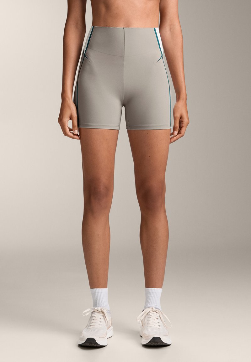 Magas derekú, világosszürke sportnadrág, teás oldalcsíkokkal, sima, rugalmas anyagból készült. Illeszkedő fazonjú és combközép hosszúságú.