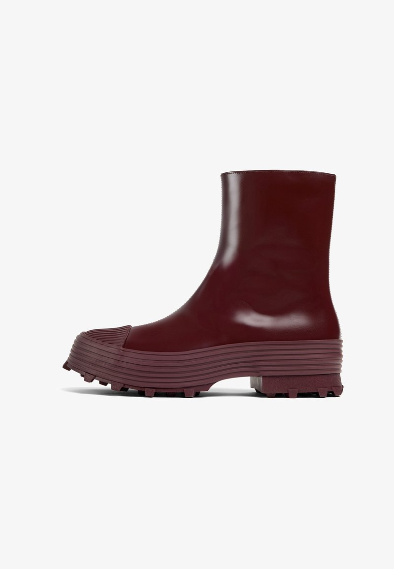 Bordeaux rubberen enkelbootjes met een forse, geribbelde zool, met een ronde neus en een gestructureerd accent aan de voorkant.
