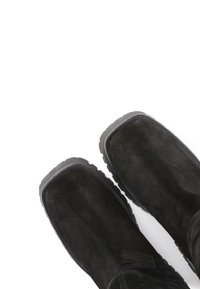Black suede boots with a soft texture, round toes, and rugged rubber soles featuring a patterned tread. Design emphasizes practicality and comfort.