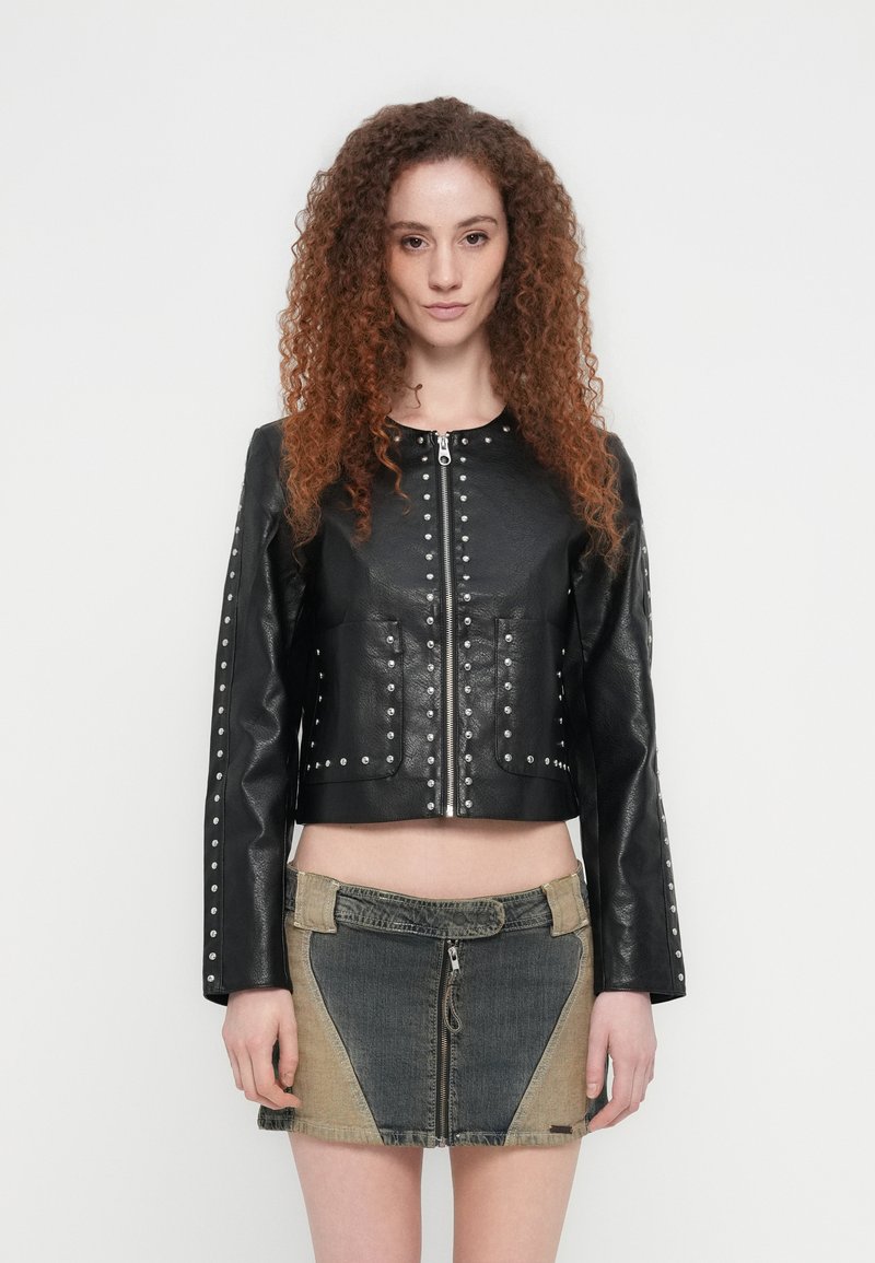 Μαύρο cropped δερμάτινο μπουφάν με ασημένιες καρφίτσες κατά μήκος του μπροστινού μέρους και των μανικιών, συνδυασμένο με μίνι φούστα τζιν με πολλούς τόνους.