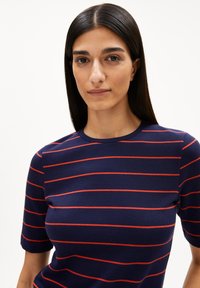 Marineblaue T-Shirt mit roten horizontalen Streifen, runder Ausschnitt und kurzen Ärmeln. Der Stoff wirkt leicht und hat eine glatte Textur.
