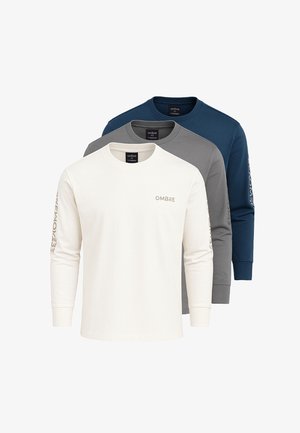 Drie T-shirts met lange mouwen en ronde hals in het wit, grijs en marineblauw met de tekst "OMBRE" op de borst en de mouw, gestapeld van voor naar achter.