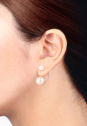 Boucles d'oreilles en perles avec un design lisse et rond. Une boucle d'oreille comporte une grande perle et l'autre une petite perle, montées sur un anneau en argent.