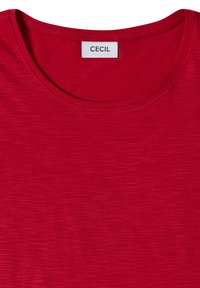 T-shirt rouge à col rond avec une petite étiquette blanche à l'intérieur du col indiquant le nom de la marque "CECIL."