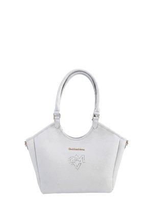 Sac à main en cuir blanc avec doubles poignées, logo doré et motif de cœur perforé sur le panneau avant, présenté sur un fond blanc.