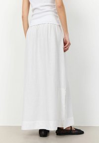 Witte linnen maxi rok met een gathers tailleband, zijnaad en een gladde textuur. Gepaard met zwarte gevlochten instappers.