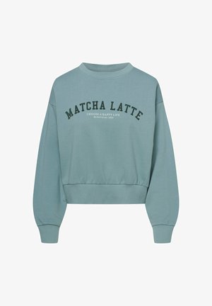 Jasnoniebieski skrócony sweatshirt z miękkiego materiału. Posiada okrągły dekolt, długie rękawy oraz wyraźny napis "MATCHA LATTE" w ciemnozielonym kolorze.